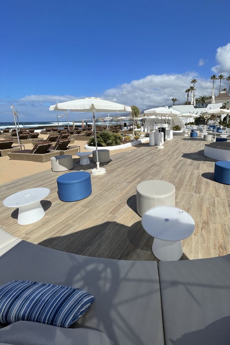 Terraza con mesas y sillas frente a la playa en un resort en Tenerife.