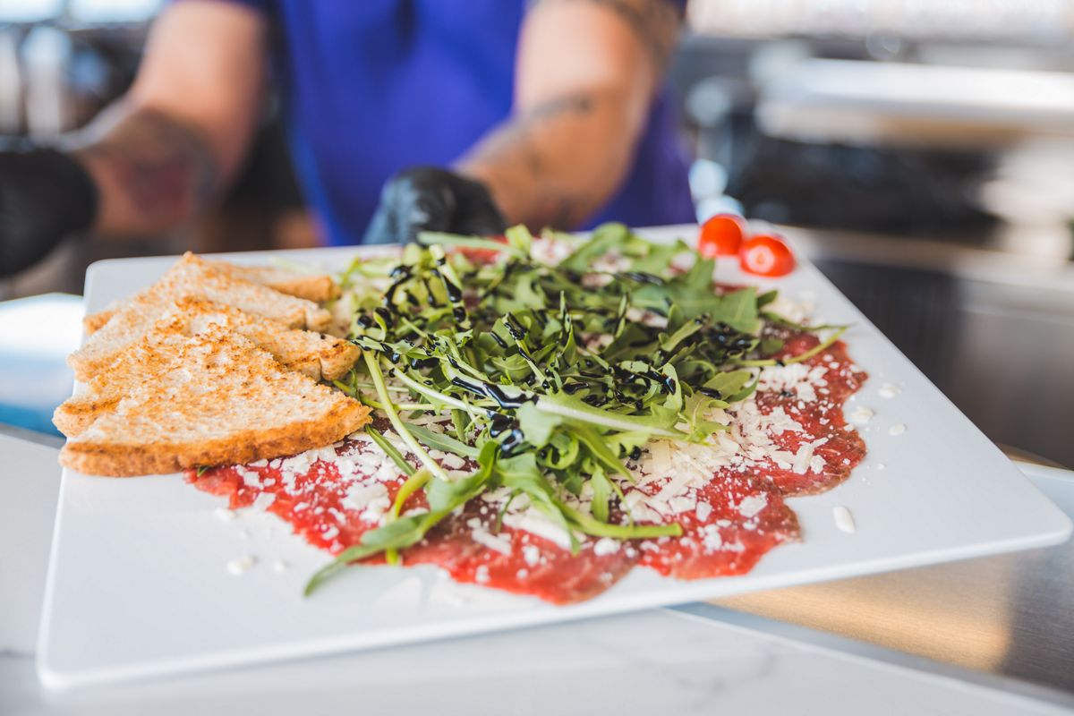 Carpaccio de ternera con rúcula y pan tostado en un restaurante de Tenerife.
