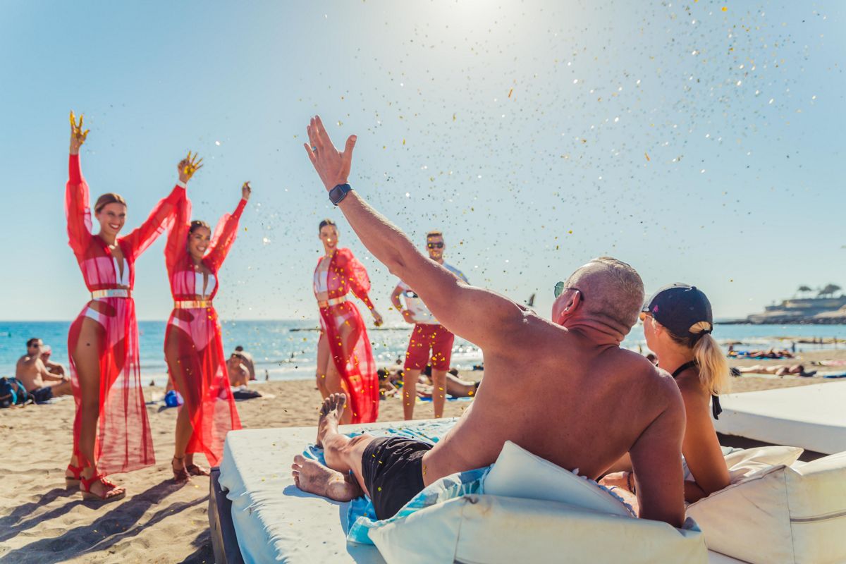Personas disfrutando en la playa con bailarinas en el Puerto de la Cruz, Tenerife.