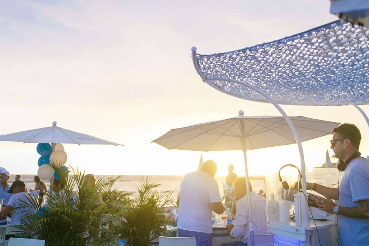 Personas disfrutando en una terraza junto al mar en Tenerife al atardecer.