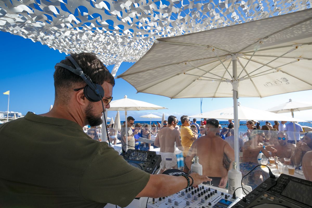 DJ en evento al aire libre en la playa de Tenerife con público disfrutando.