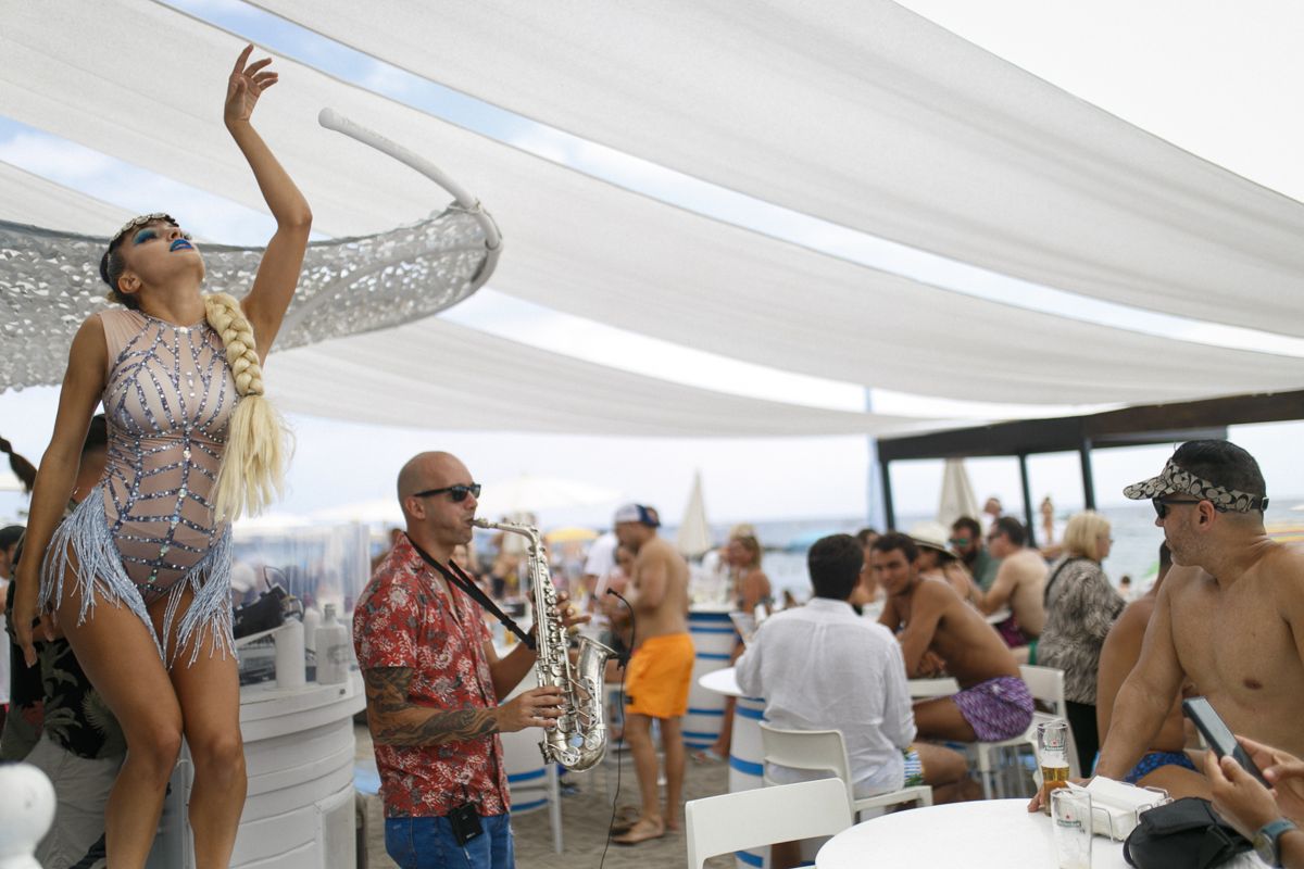 Bailarina y músico tocando saxofón en evento al aire libre en playa de Tenerife.