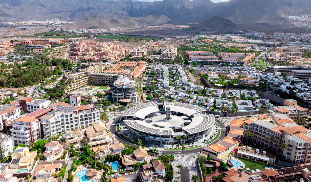 Vista aérea de Costa Adeje en Tenerife con edificios y montañas al fondo.