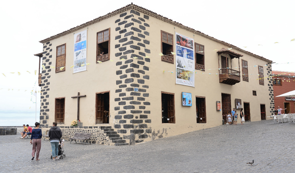 Edificio histórico en Garachico, Tenerife con ventanas de madera y carteles en la fachada.