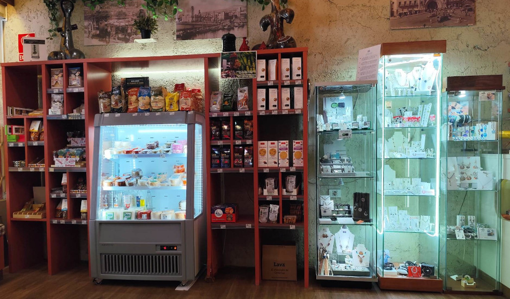 Estantes con snacks, nevera con lácteos y vitrinas con joyería en tienda de Tenerife.