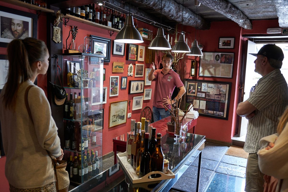 Hombre explicando sobre vinos a turistas, rodeado de botellas y decoraciones en Tenerife.