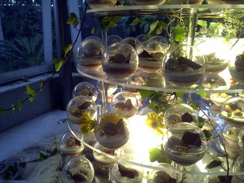 Postres en esferas de cristal en un estante decorado con hojas y luz, en Tenerife.