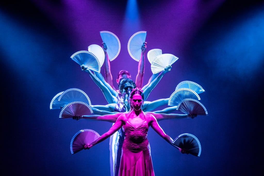 Bailarines en escena con abanicos iluminados en un espectáculo en Tenerife.