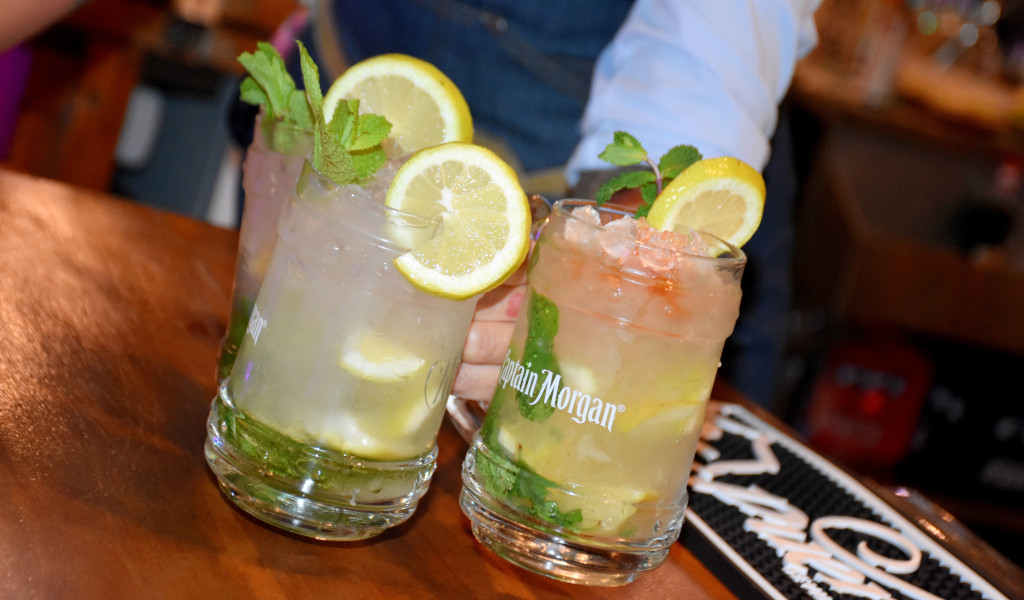 Dos cócteles con rodajas de limón y menta en vasos Captain Morgan en un bar de Tenerife.