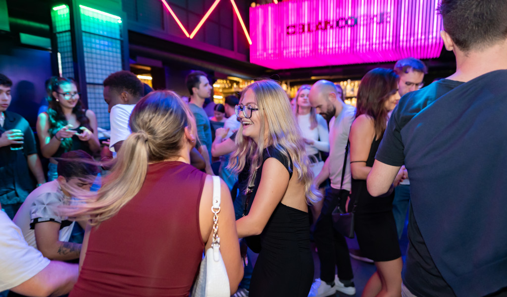 Personas socializando y bailando en un club nocturno iluminado en Tenerife.
