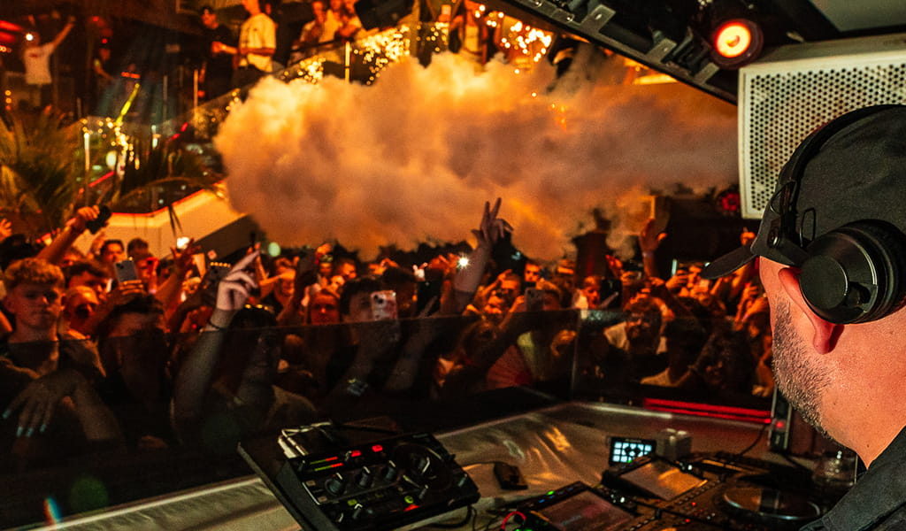 DJ tocando en vivo frente a una multitud animada en un club de Tenerife.
