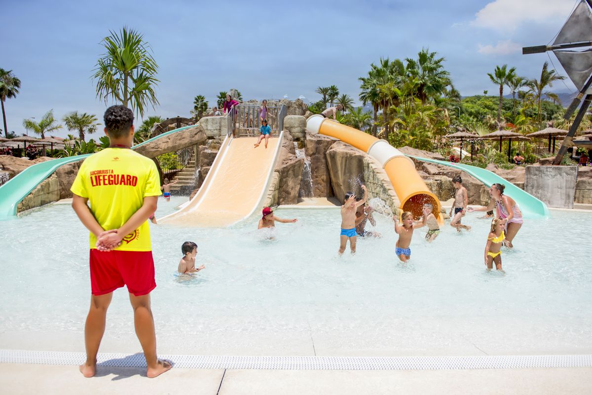 Salvavidas vigilando a niños jugando en toboganes del parque acuático en Tenerife.