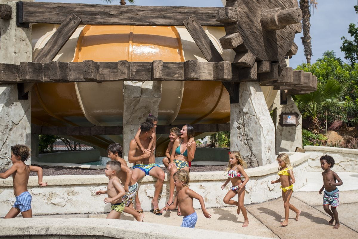 Niños jugando en parque acuático en Tenerife bajo gran tobogán.