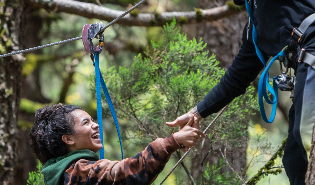 Persona riendo mientras realiza tirolina en un bosque de Tenerife.