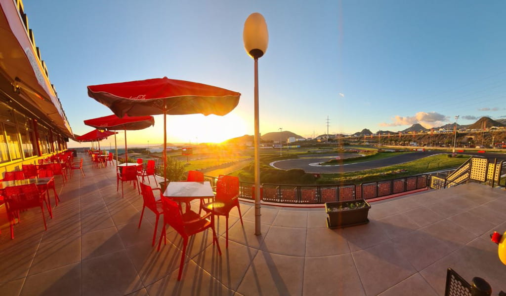 Terraza de restaurante con mesas rojas y vista al atardecer en un circuito en Tenerife.