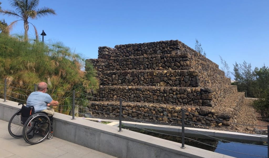 Persona en silla de ruedas observando pirámide en Güímar, Tenerife.