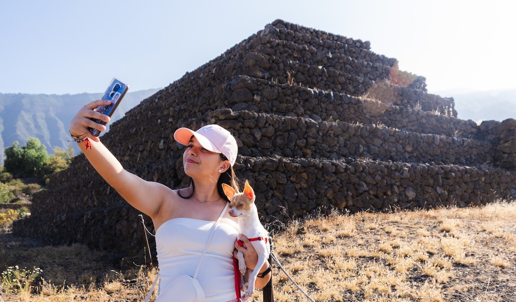 Persona tomando una selfie con un perro frente a las Pirámides de Güímar en Tenerife.