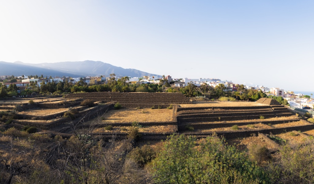Pirámides de Güímar en Tenerife con montañas y ciudad al fondo.