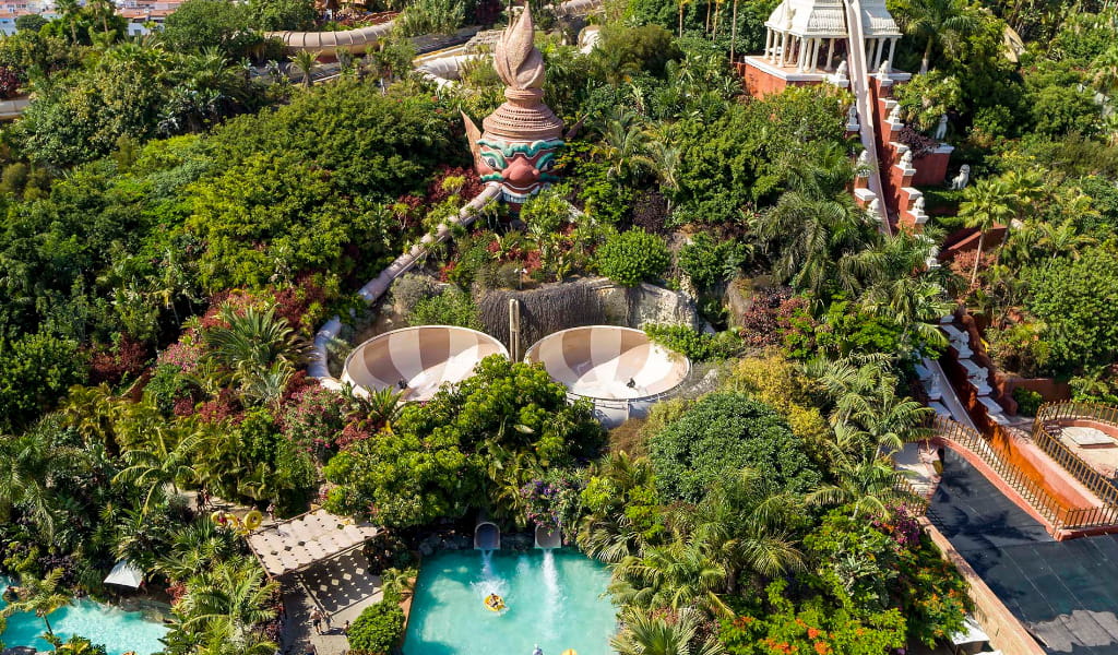 Vista aérea del parque acuático Siam Park en Tenerife con toboganes y vegetación exuberante.