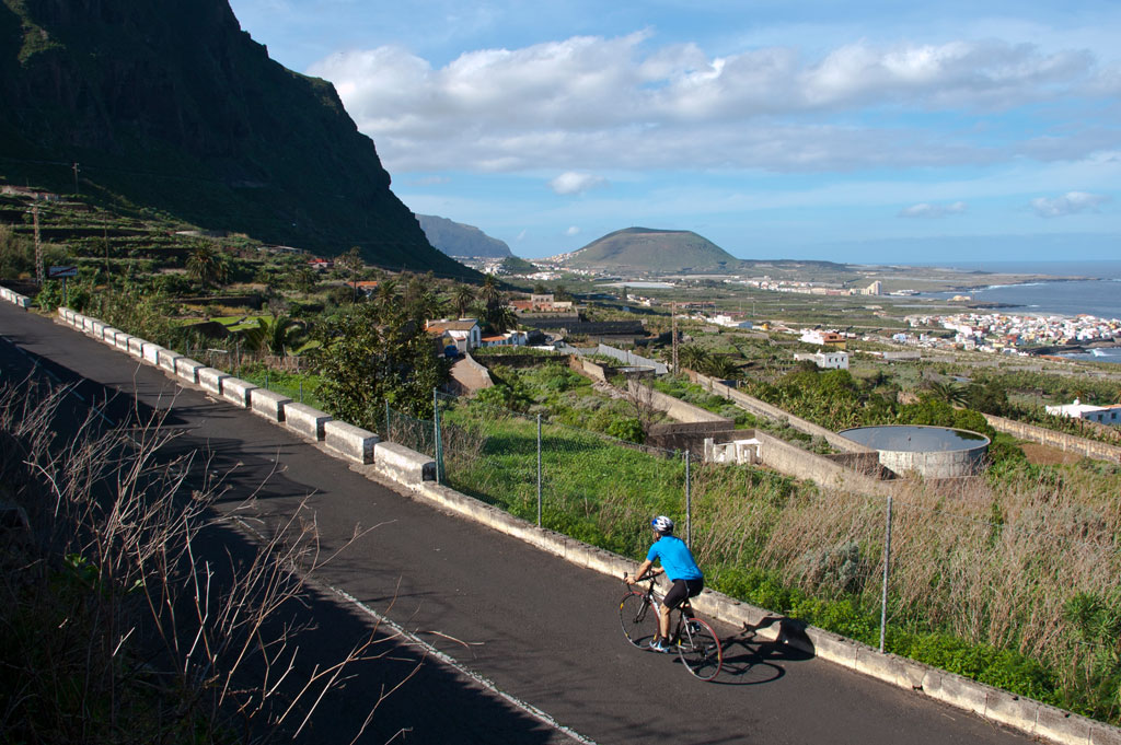 Ciclista en carretera con vista al paisaje montañoso y costero en Tenerife.