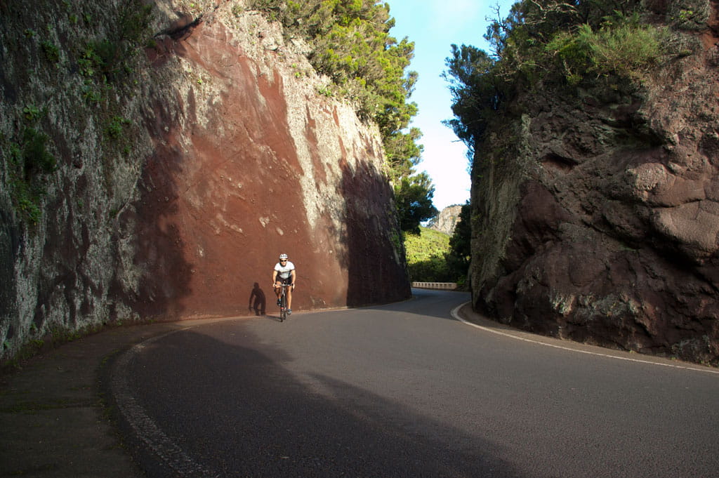 Ciclista en carretera rodeada de formaciones rocosas en Tenerife.