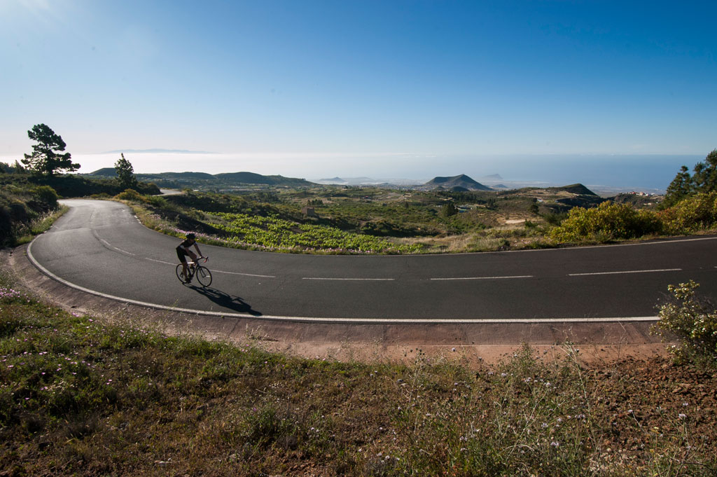 Ciclista en una carretera con vistas al paisaje montañoso de Tenerife.