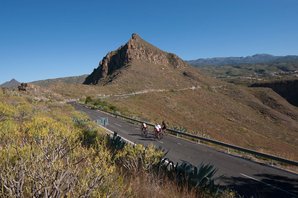 Ciclistas recorren camino en paisaje montañoso de Tenerife.