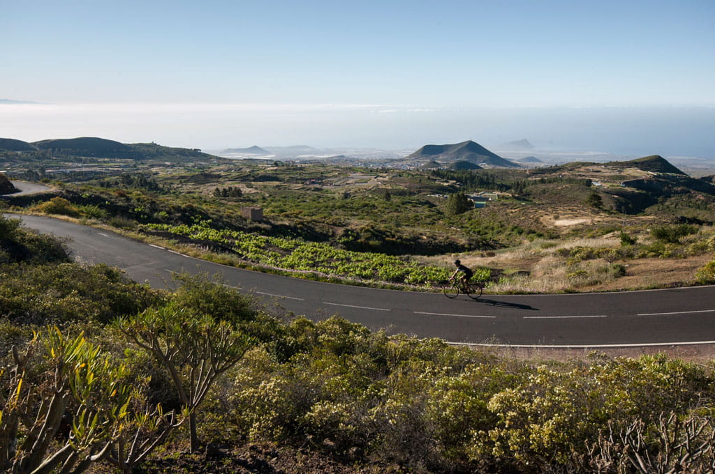 Ciclista en carretera curvada con vista panorámica de Tenerife.