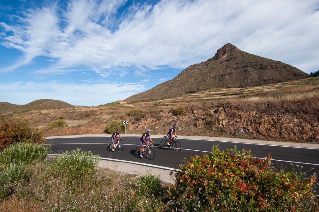 Ciclistas en carretera montañosa cerca de un pico en Tenerife.