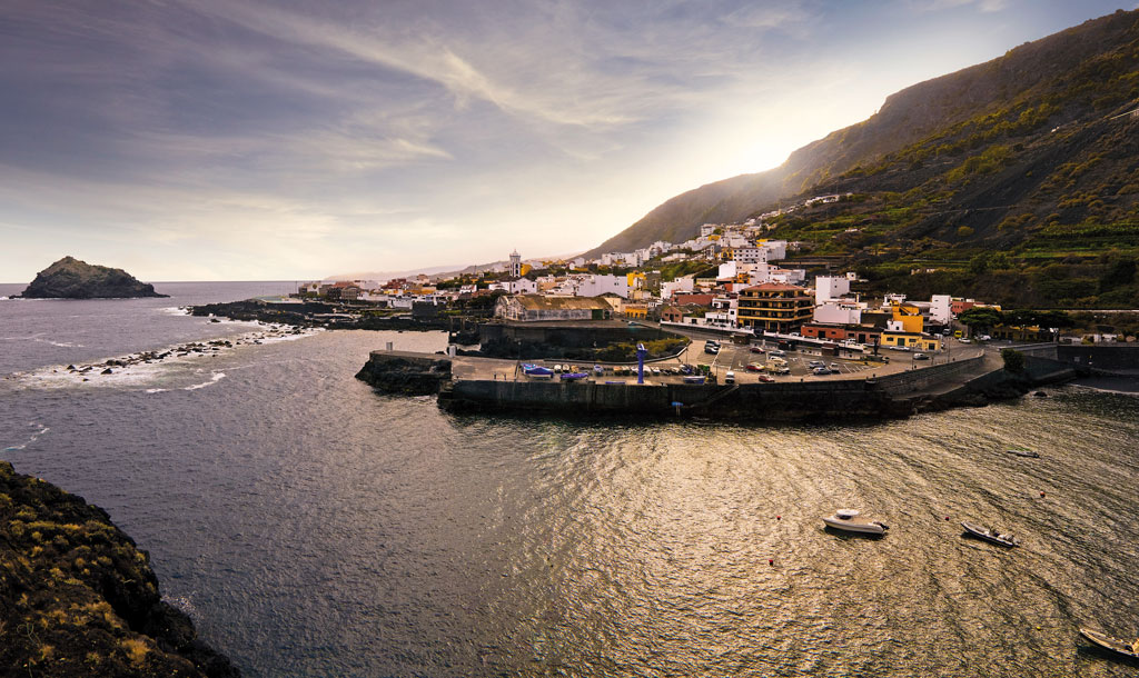 Pueblo costero junto a las montañas en Tenerife al atardecer.