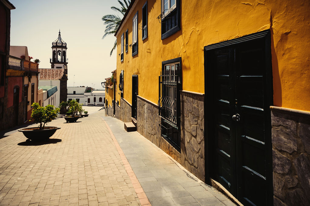 Calle empedrada y edificios coloridos en La Orotava, Tenerife. Torre de iglesia al fondo.