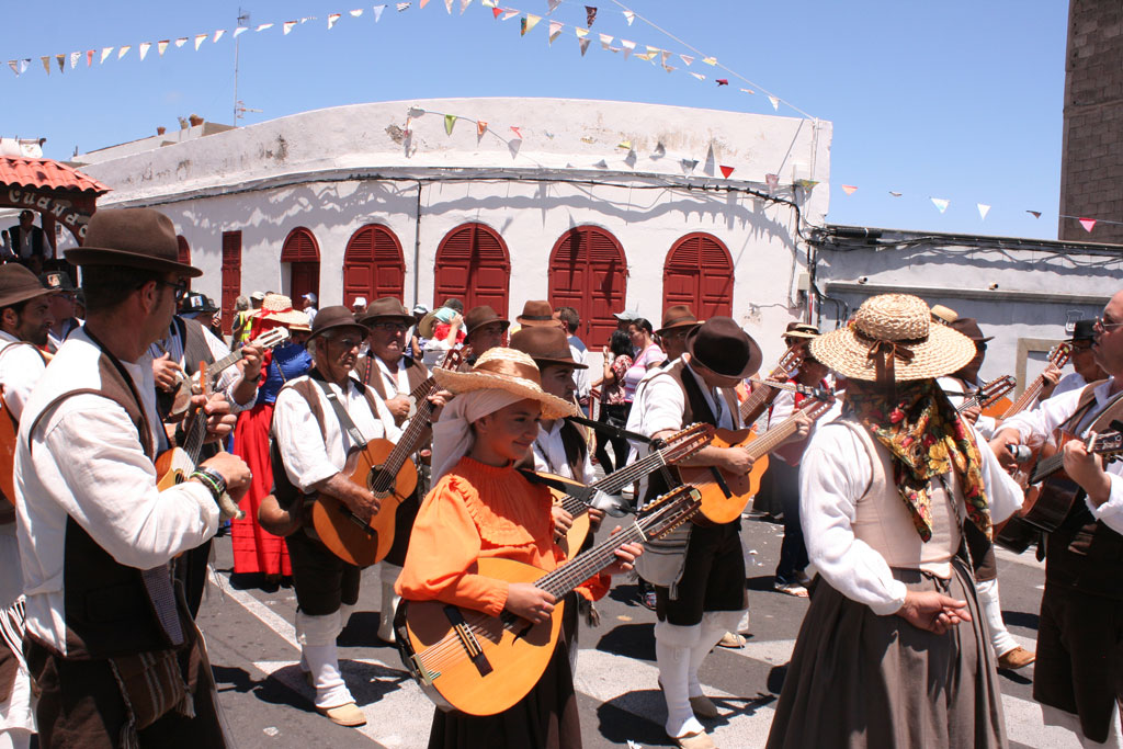 Grupo de personas con trajes tradicionales tocando guitarras en una fiesta en Tenerife.