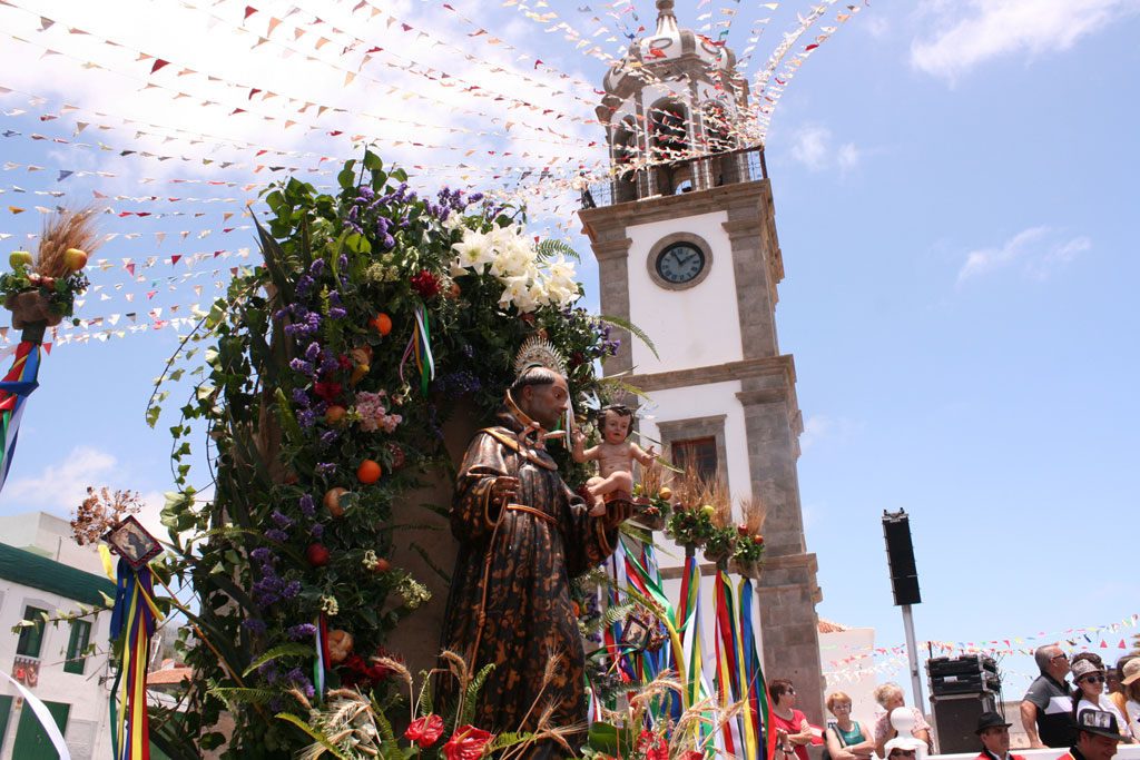 Fiesta en La Orotava con torre del reloj y decoración festiva.