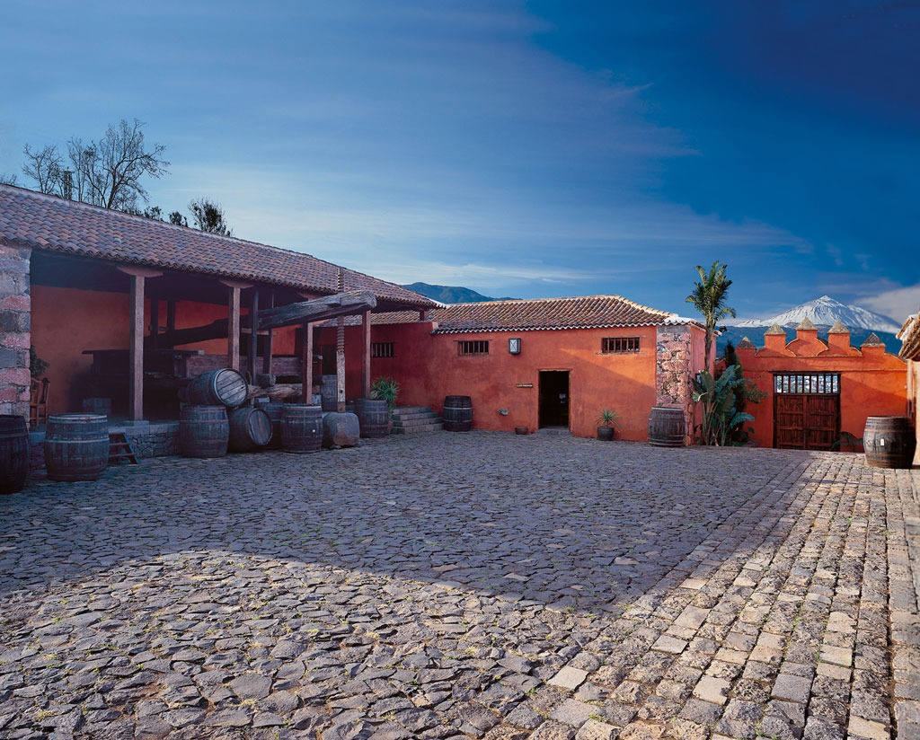 Patio de una bodega tradicional en Tenerife con barriles y vistas al Teide.