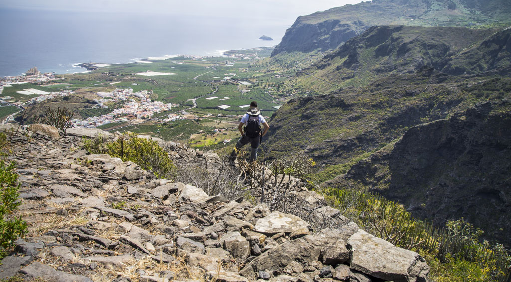 Excursionista en montaña con vista a paisaje costero en Tenerife.