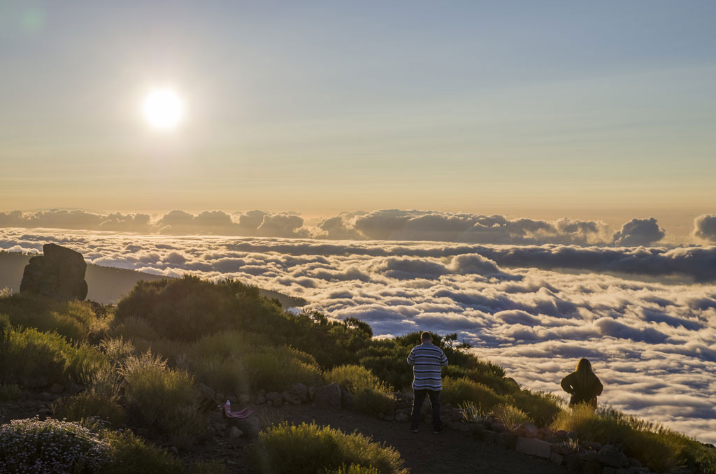 Personas contemplando un atardecer sobre las nubes en el Parque Nacional del Teide, Tenerife.
