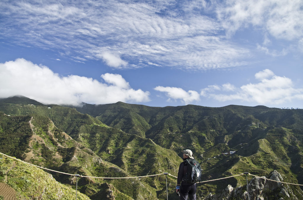 Persona observando las montañas verdes de Anaga en Tenerife bajo un cielo parcialmente nublado.