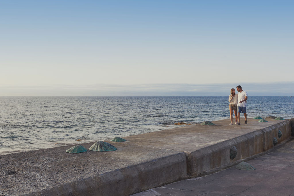 Pareja caminando por el muelle junto al mar en Tenerife.