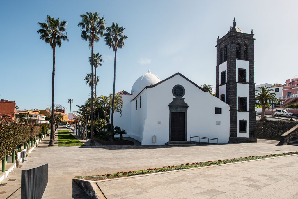 Iglesia de San Juan Bautista con su campanario y palmeras alrededor en La Orotava, Tenerife.