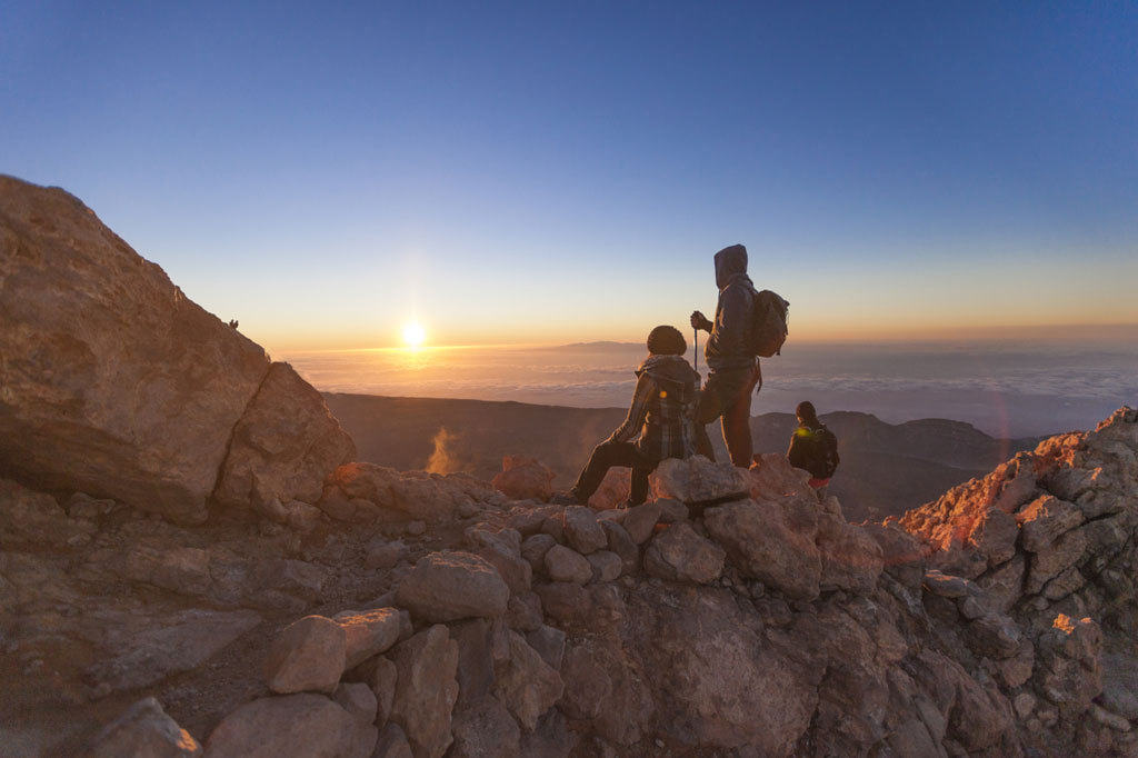 Senderistas contemplando el amanecer desde el Pico del Teide en Tenerife.