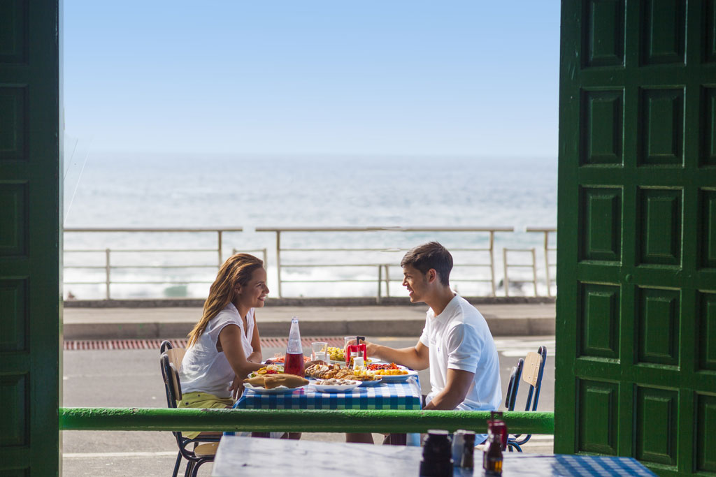 Pareja comiendo en una terraza con vista al mar en Tenerife.