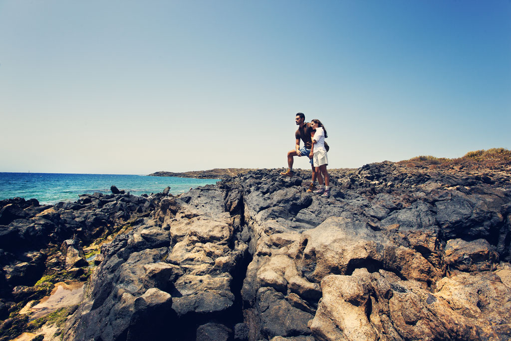 Pareja observa el mar desde costa rocosa en Tenerife.