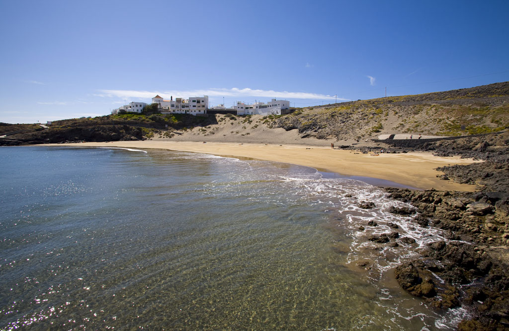 Playa con arena dorada y edificios al fondo en la costa de Tenerife.
