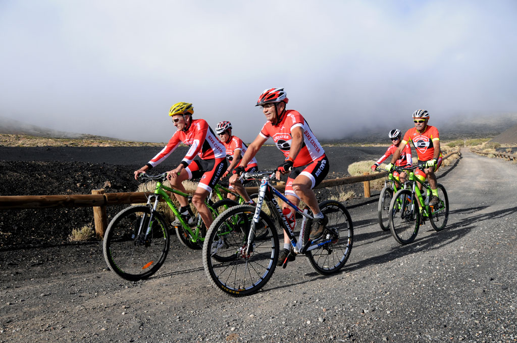 Ciclistas en camino de montaña en Tenerife, vestidos con uniforme rojo y negro.