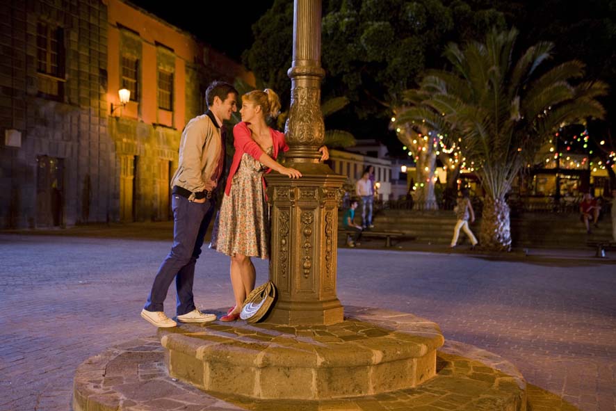 Pareja conversando junto a una farola en una plaza iluminada en La Laguna, Tenerife.