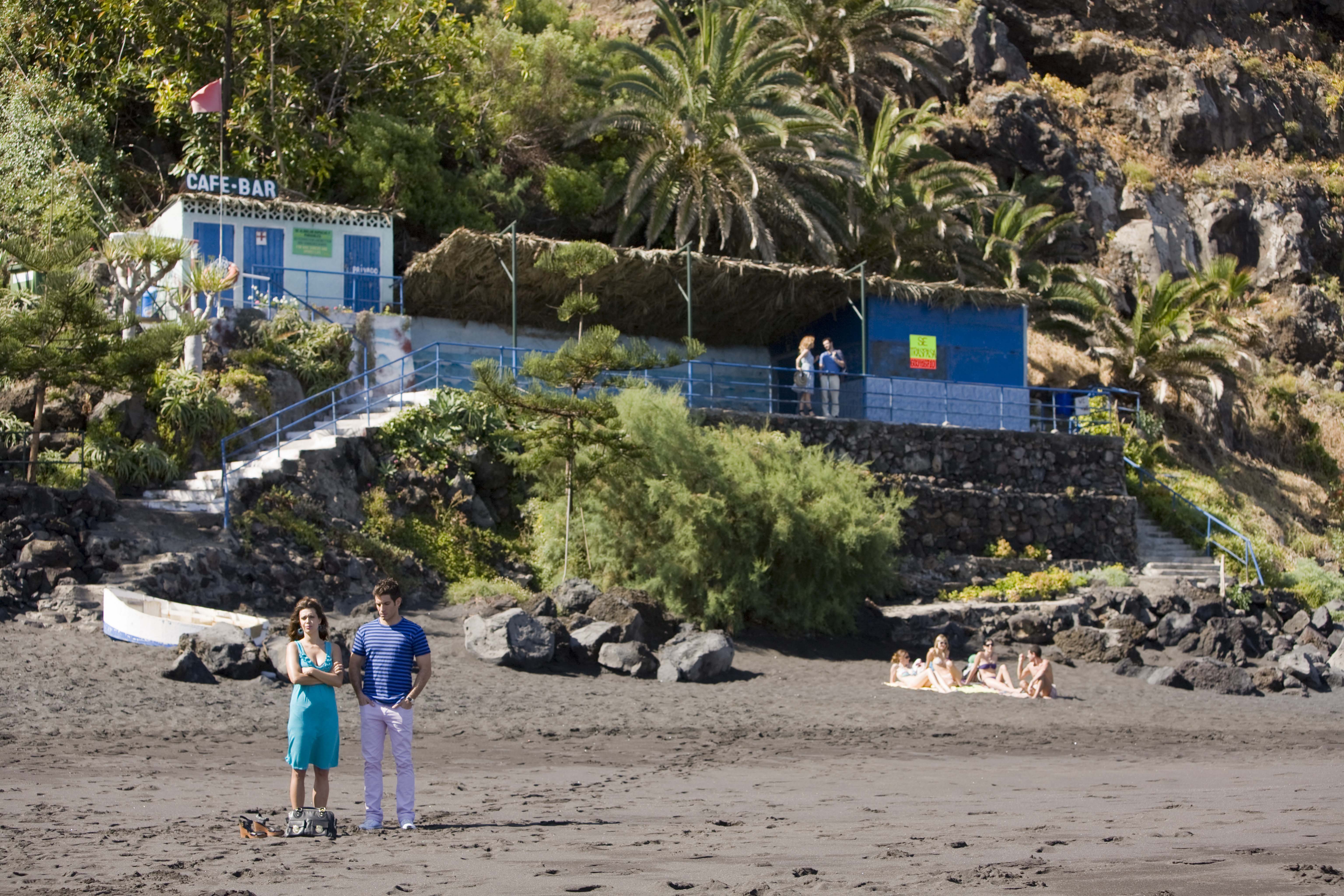 Pareja en la playa frente a un café-bar en Puerto de la Cruz, Tenerife.