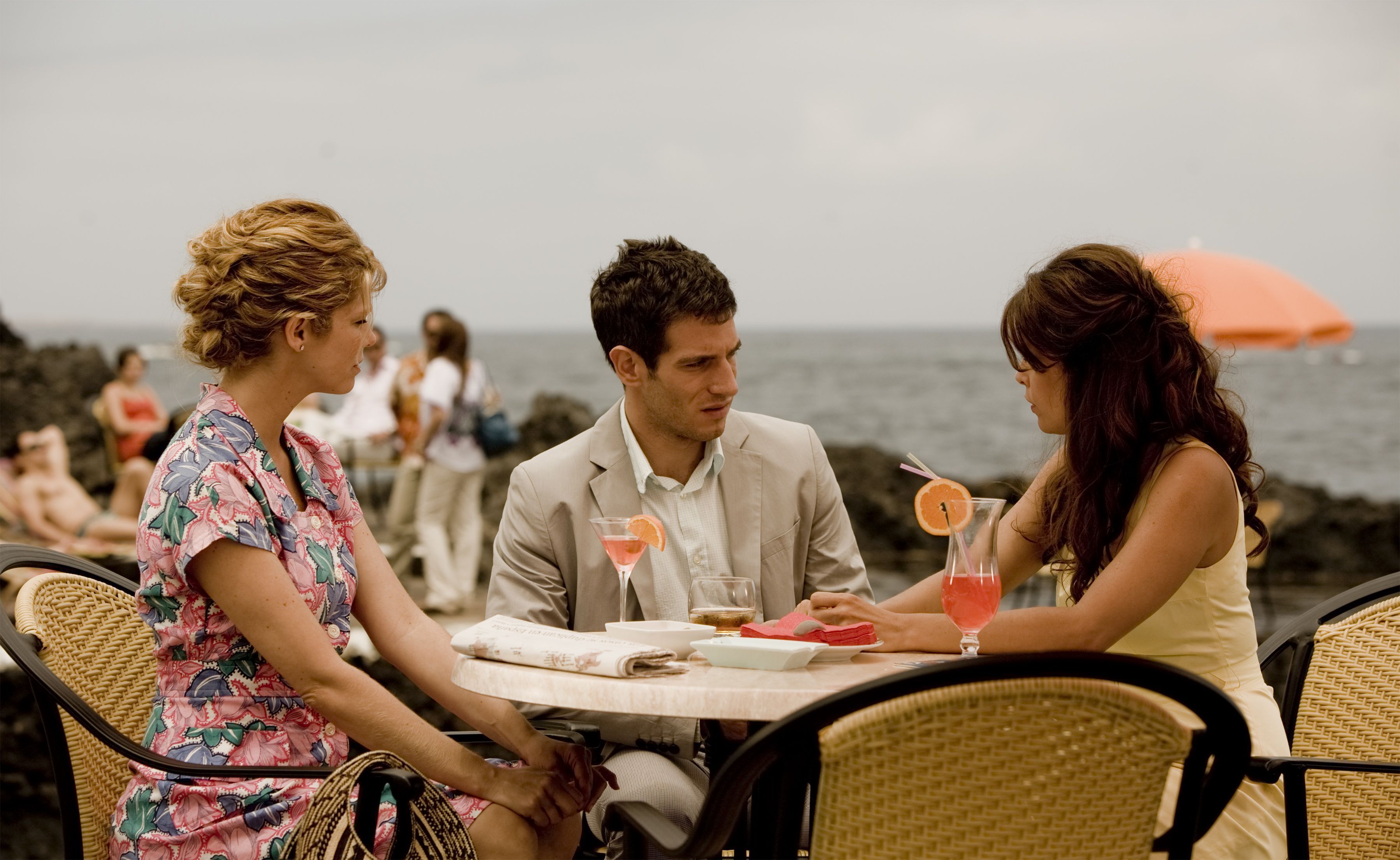Personas conversando en una terraza junto al mar en Tenerife. Bebidas en la mesa.