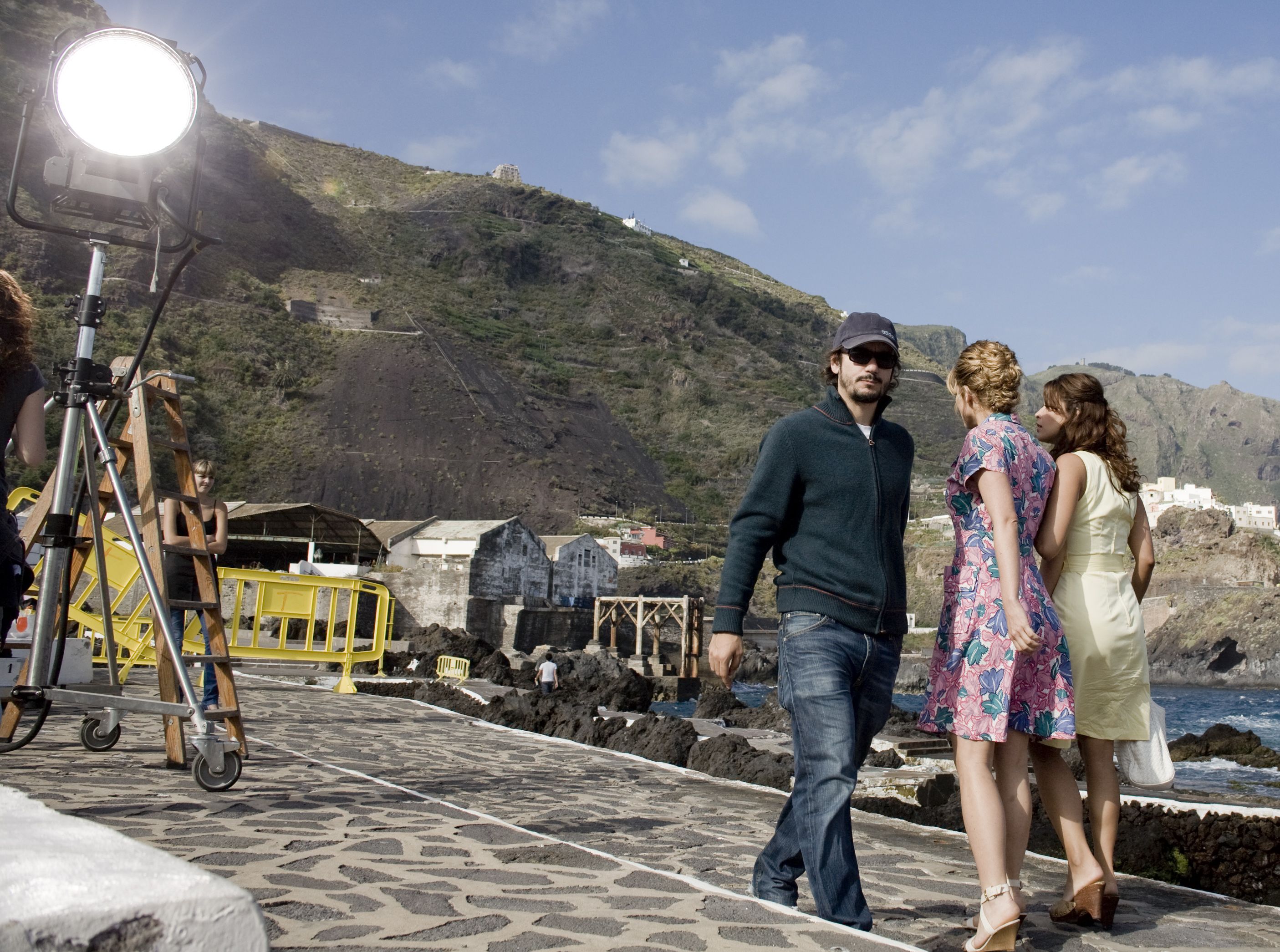 Personas en un rodaje en Garachico, Tenerife, con equipo de filmación y paisaje montañoso.