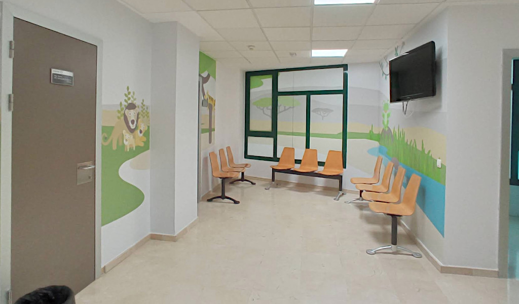 Sala de espera con sillas naranjas y murales coloridos en Tenerife.