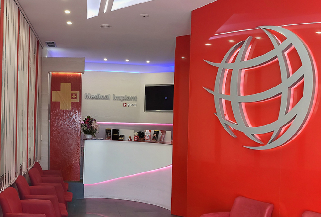 Recepción de Medical Implant Group con sillas rojas y logotipo en Santa Cruz, Tenerife.